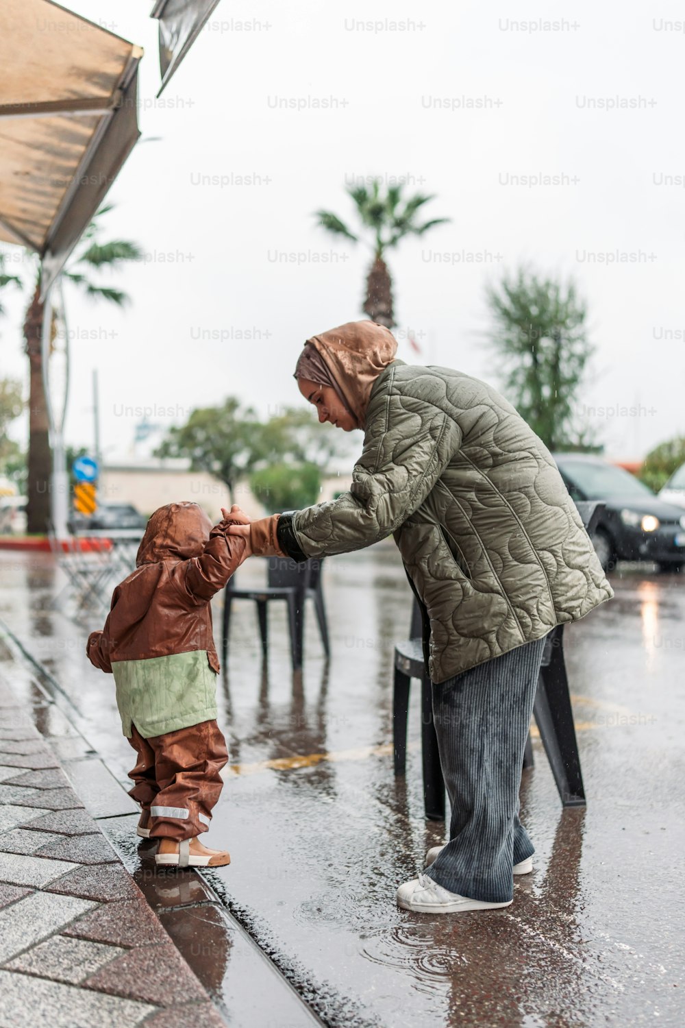 a woman and a child standing in the rain
