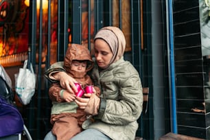 a woman and child sitting on a bench looking at a cell phone