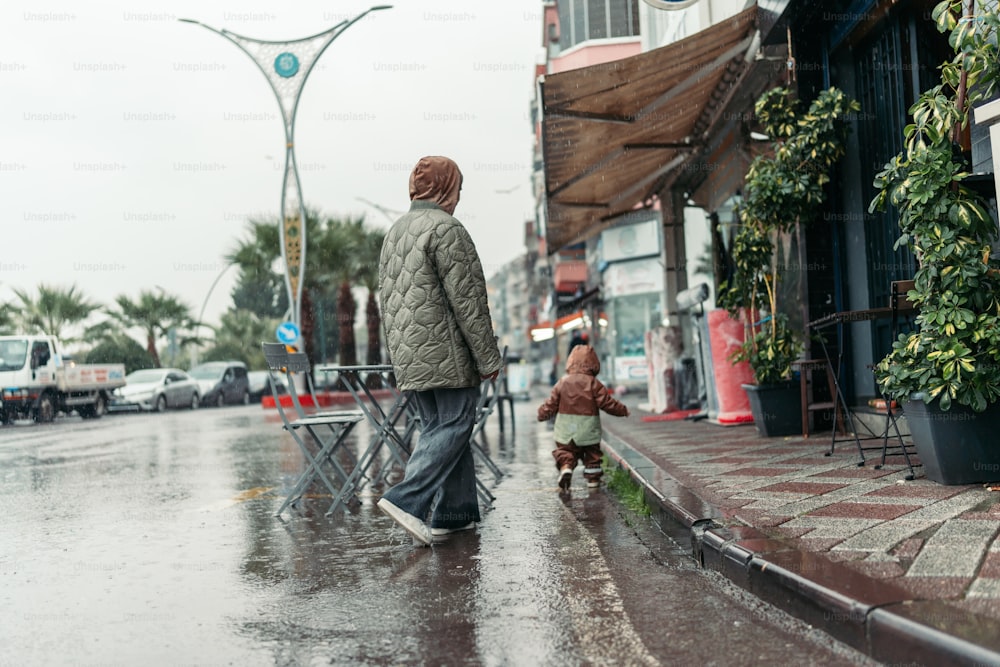Ein Mann und ein Kind gehen im Regen eine Straße entlang