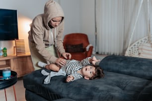 una donna in piedi sopra un bambino sdraiato su un divano