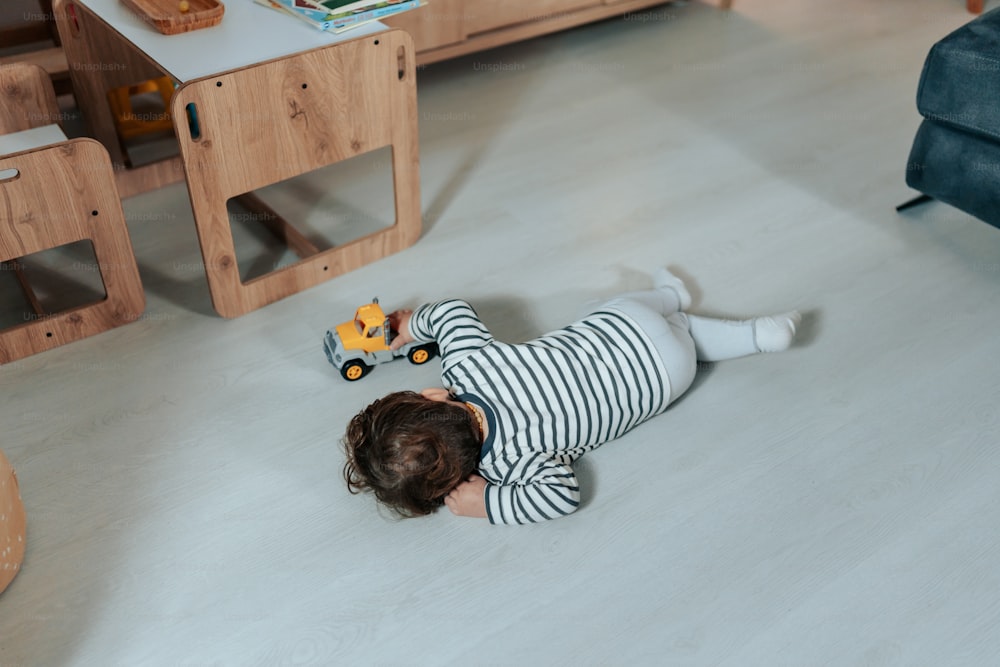 Un niño pequeño tumbado en el suelo jugando con un juguete