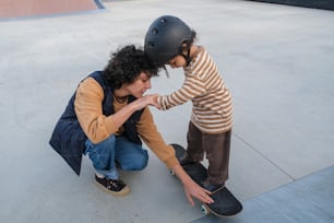 Une femme agenouillée à côté d’un enfant sur une planche à roulettes