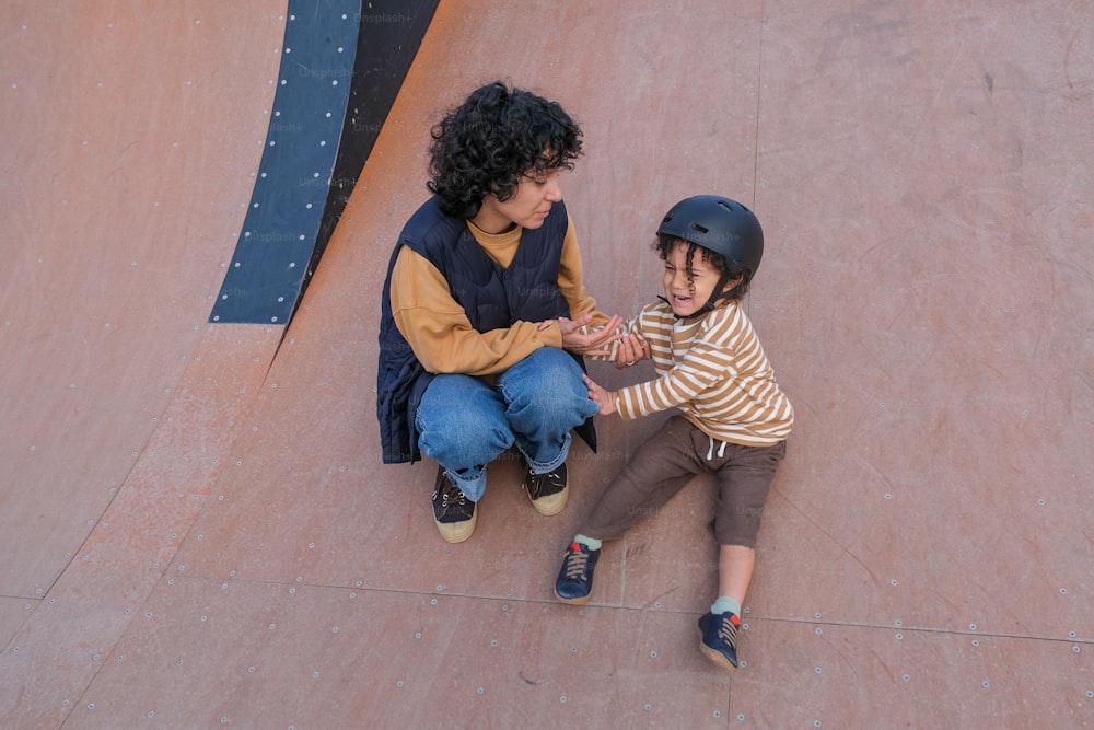 a little boy holding the hand of a woman on a skateboard ramp