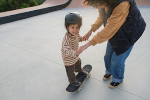 eine Frau, die einem Kind auf einem Skateboard hilft