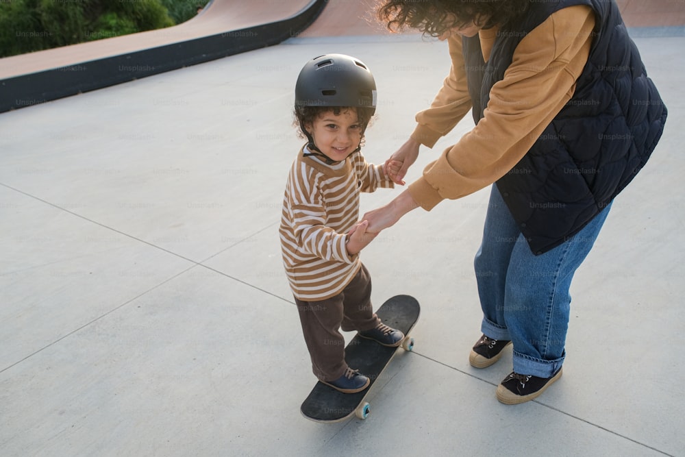 a woman helping a child on a skateboard