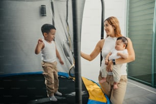 a woman and two children playing on a trampoline