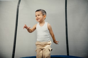 a young boy standing on top of a trampoline