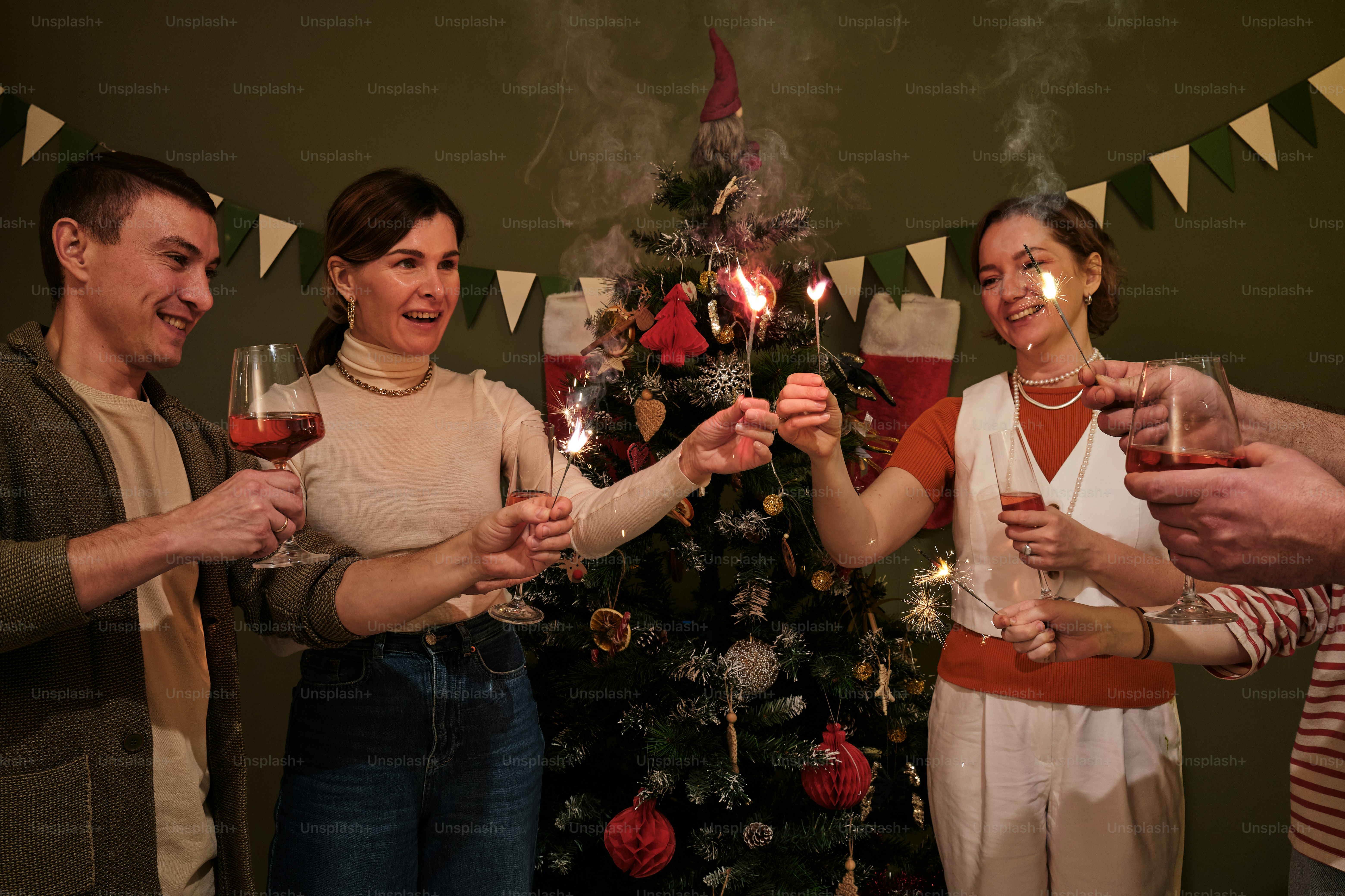 a group of people holding wine glasses in front of a christmas tree