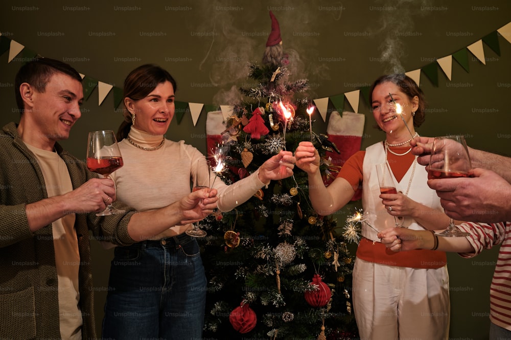 a group of people holding wine glasses in front of a christmas tree
