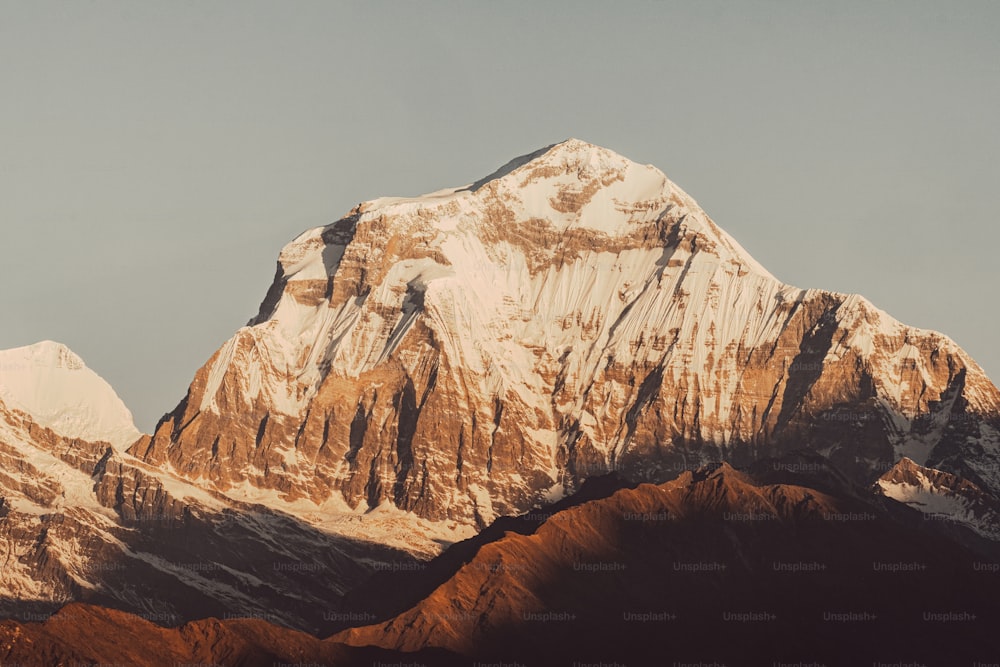 a snow covered mountain with a plane flying in the sky