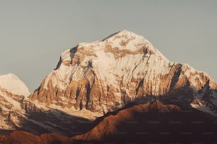 a snow covered mountain with a plane flying in the sky