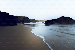 a sandy beach with waves coming in to shore