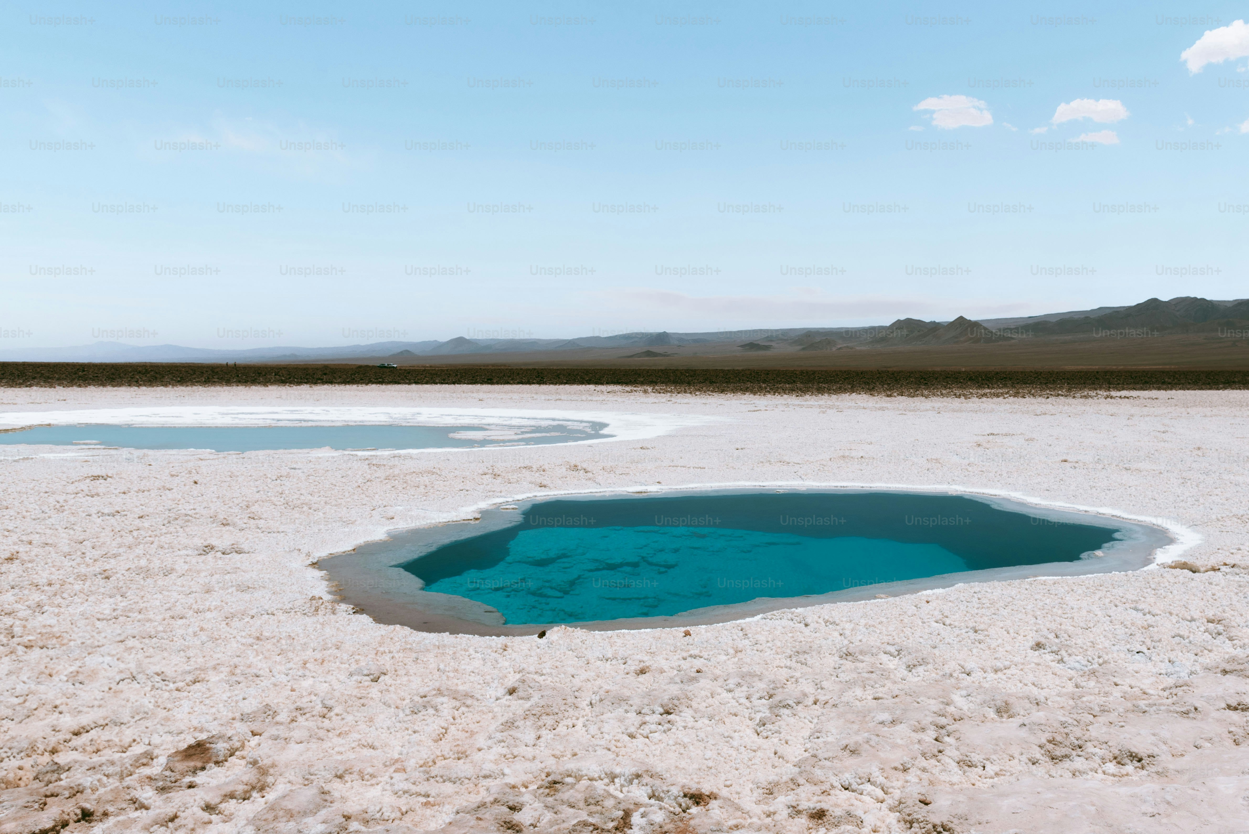 a blue pool of water in the middle of a desert