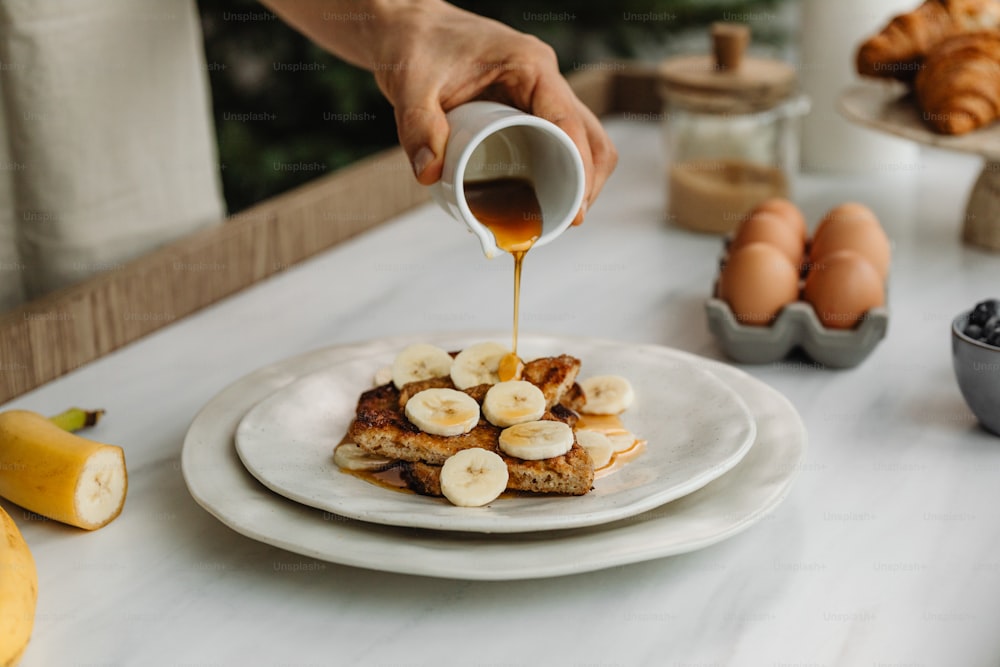 a person pouring syrup on a plate of food