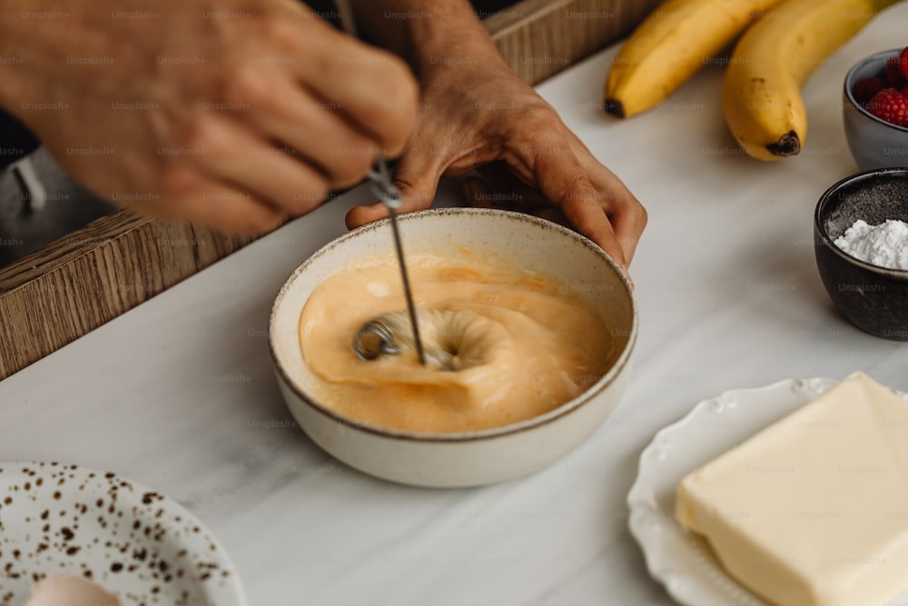 a person mixing batter in a bowl on a table