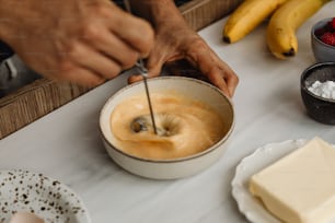 a person mixing batter in a bowl on a table