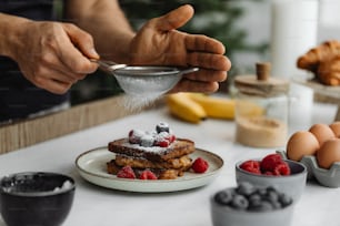 a person scooping sugar onto a plate of french toast