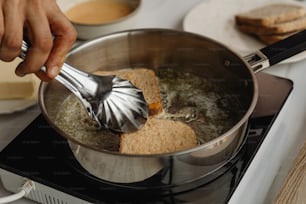 a person stirring a pot of food on a stove