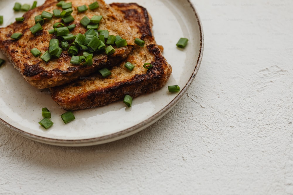 two pieces of toast with green onions on a plate