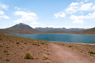 uma estrada de terra que leva a um lago com montanhas ao fundo