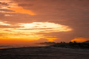 the sun is setting on the beach with people walking on the sand