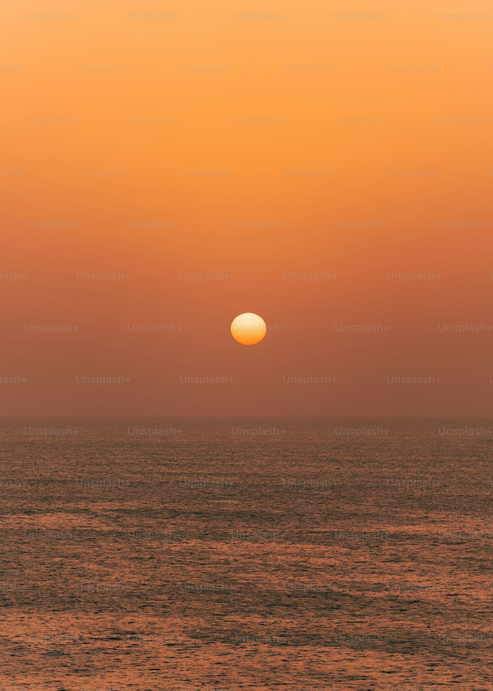 the sun is setting over the ocean on a hazy day