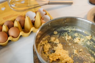 a metal bowl filled with food next to eggs