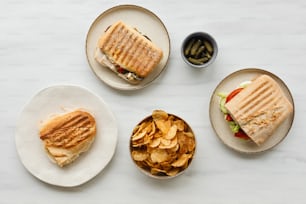 a table topped with plates of food and bowls of chips