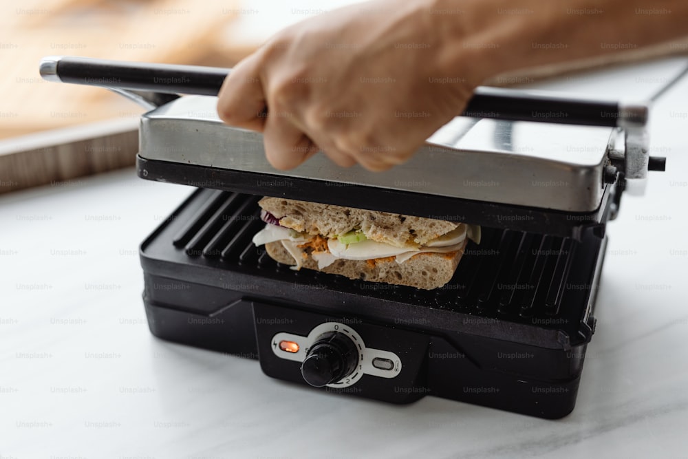 a person is putting a sandwich on top of a grill