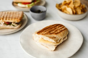 une assiette blanche garnie d’un sandwich et de frites