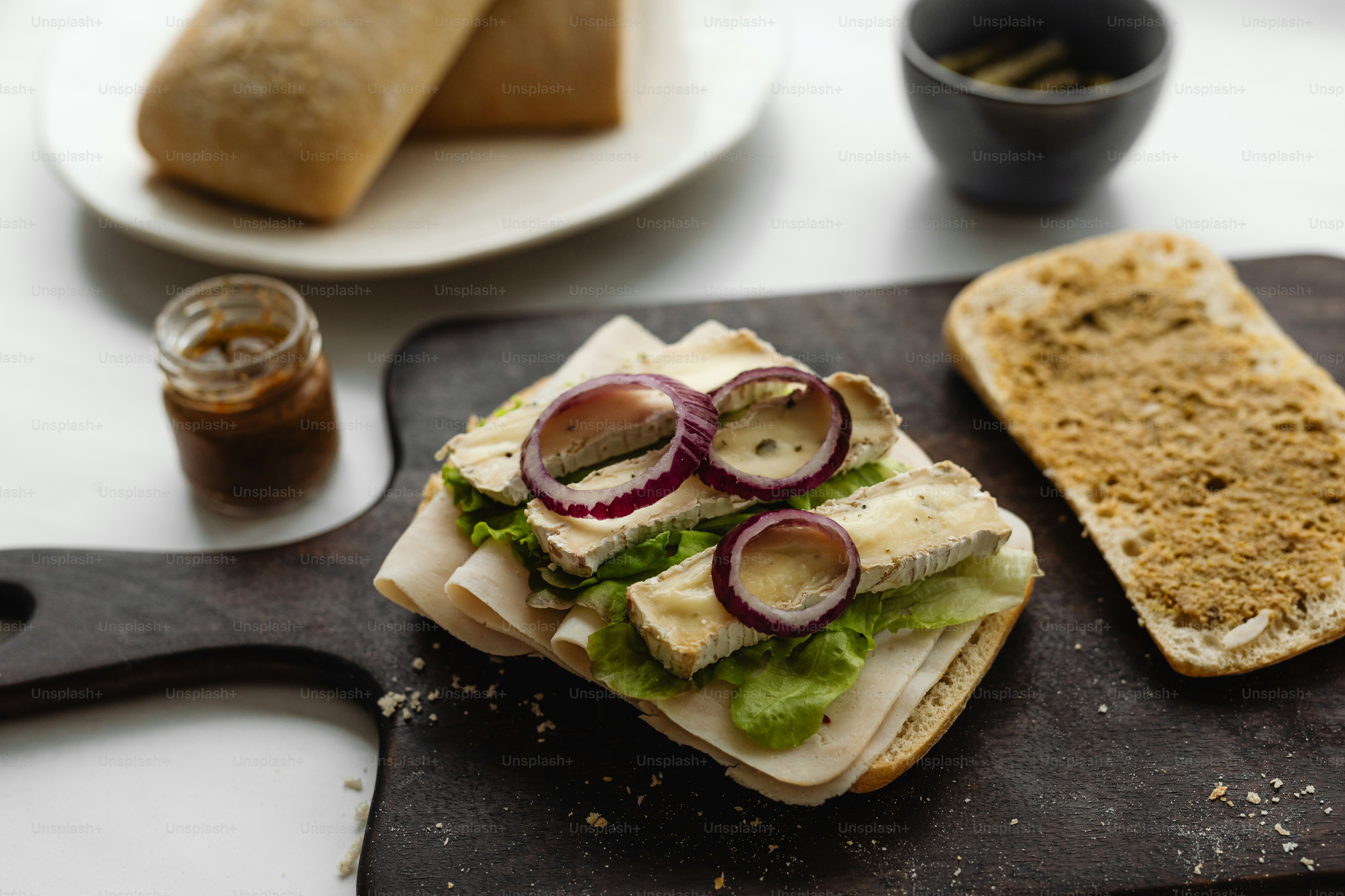 a sandwich with lettuce, onions and cheese on a cutting board