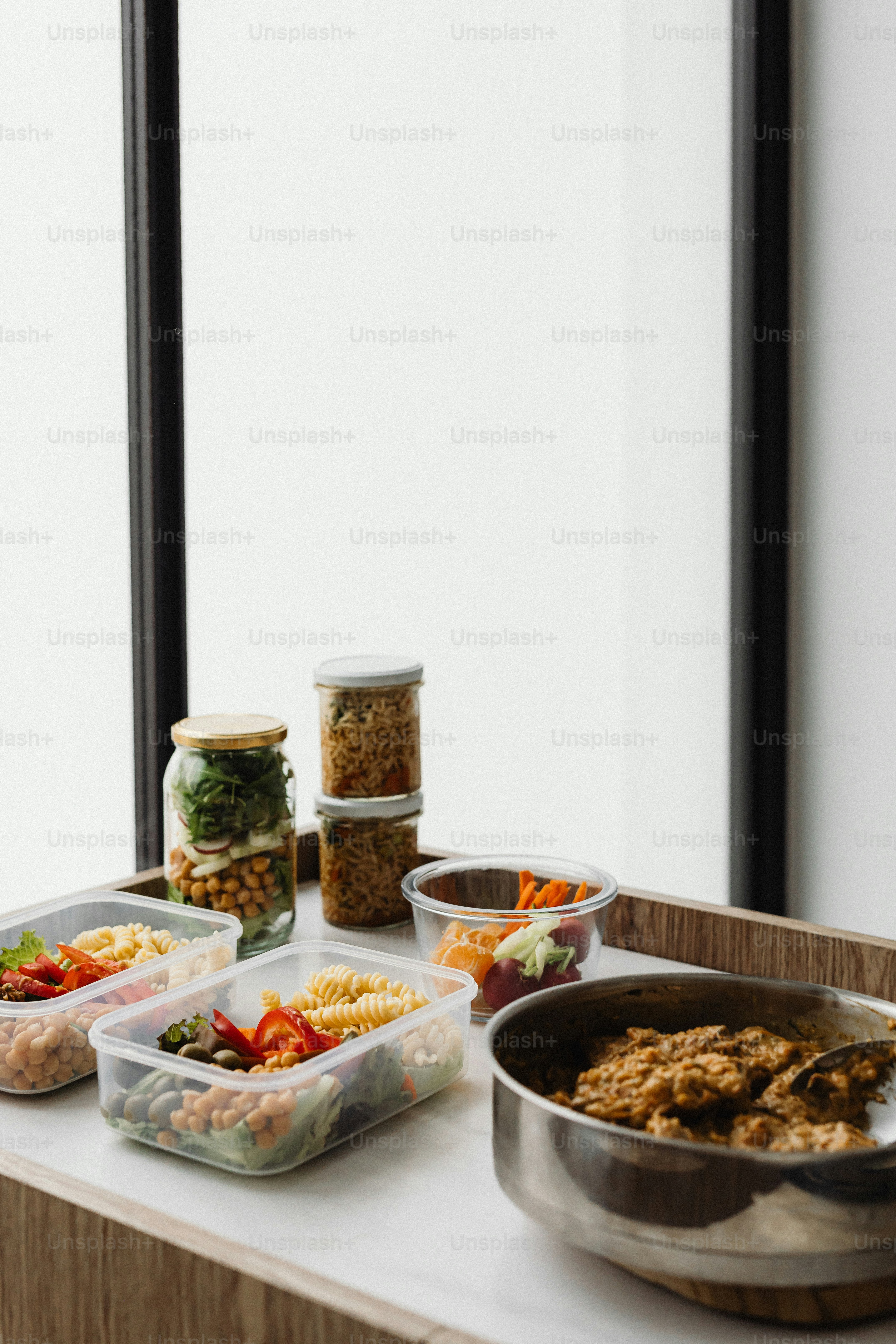 a table topped with containers of food next to a window