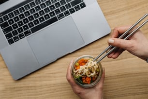 a person holding chopsticks over a bowl of food