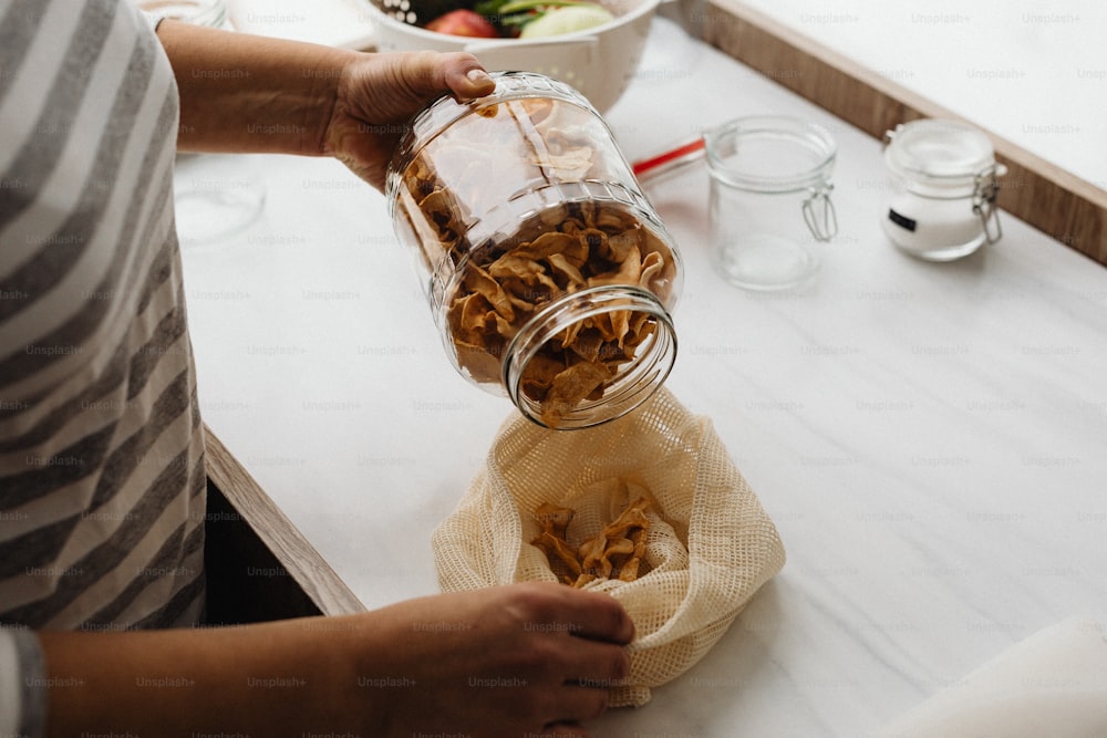 a person pours a jar of food into a bag