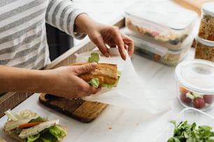 a person holding a sandwich on a cutting board