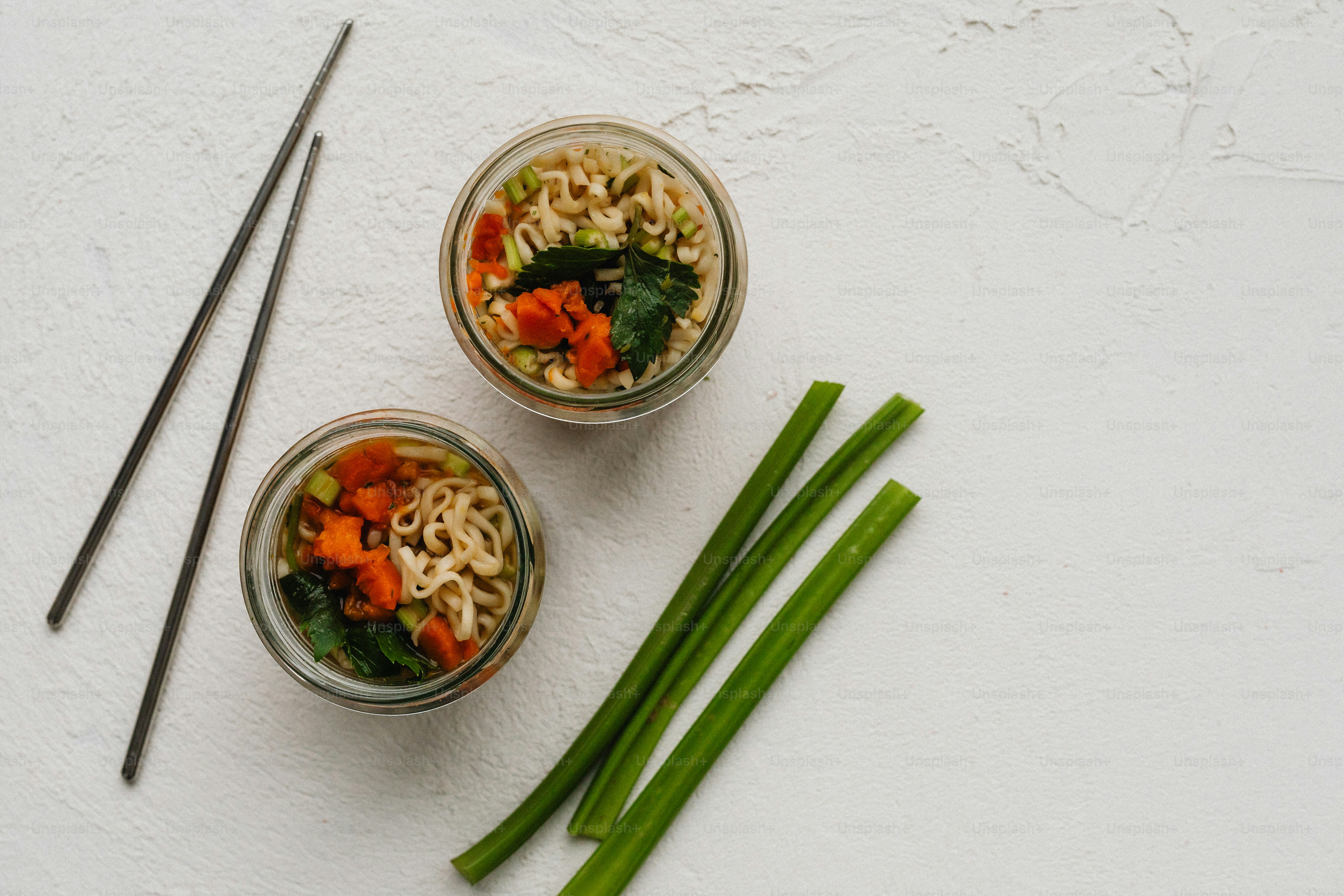 dos cuencos de fideos y verduras con palillos