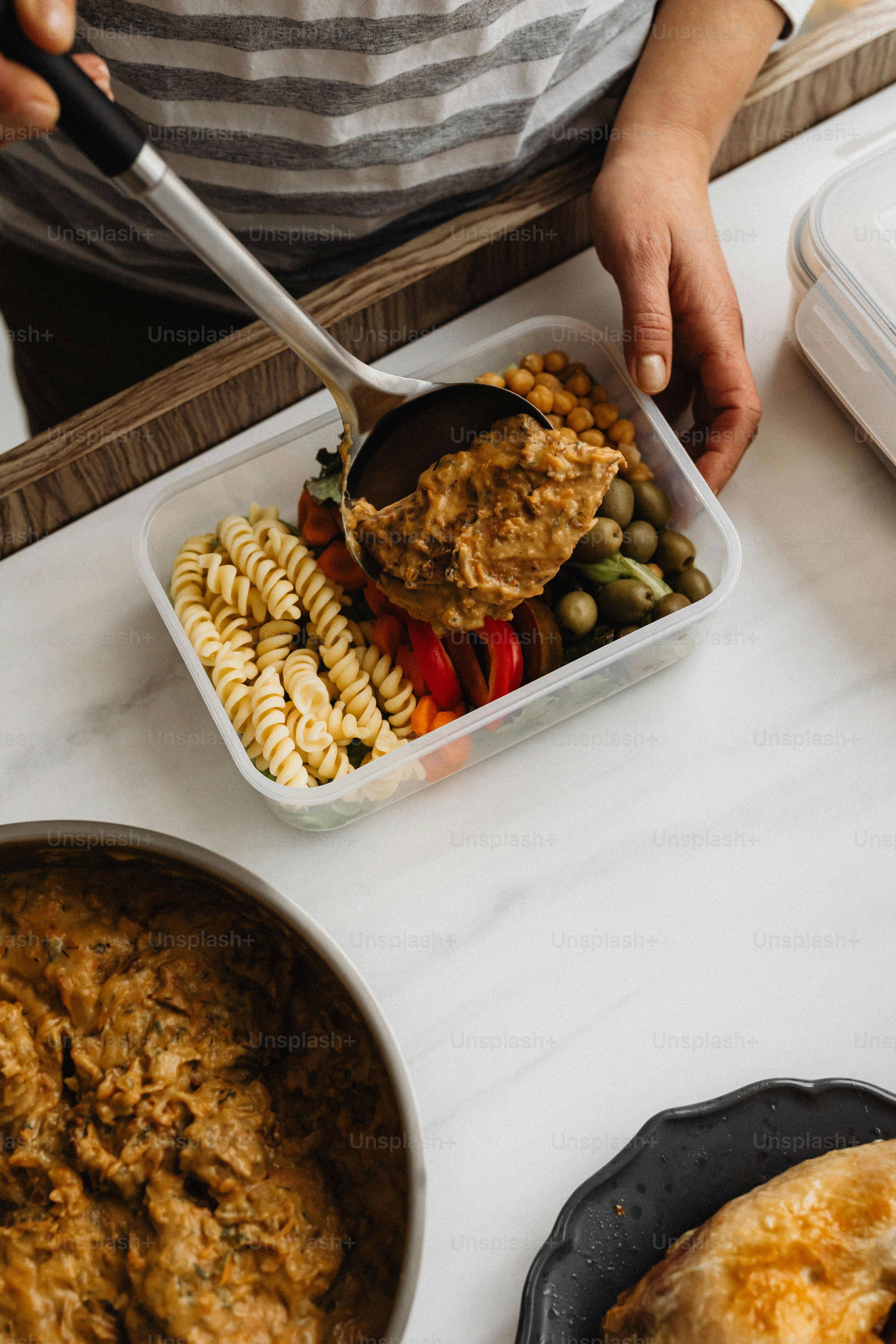 a person holding a spoon over a container of food