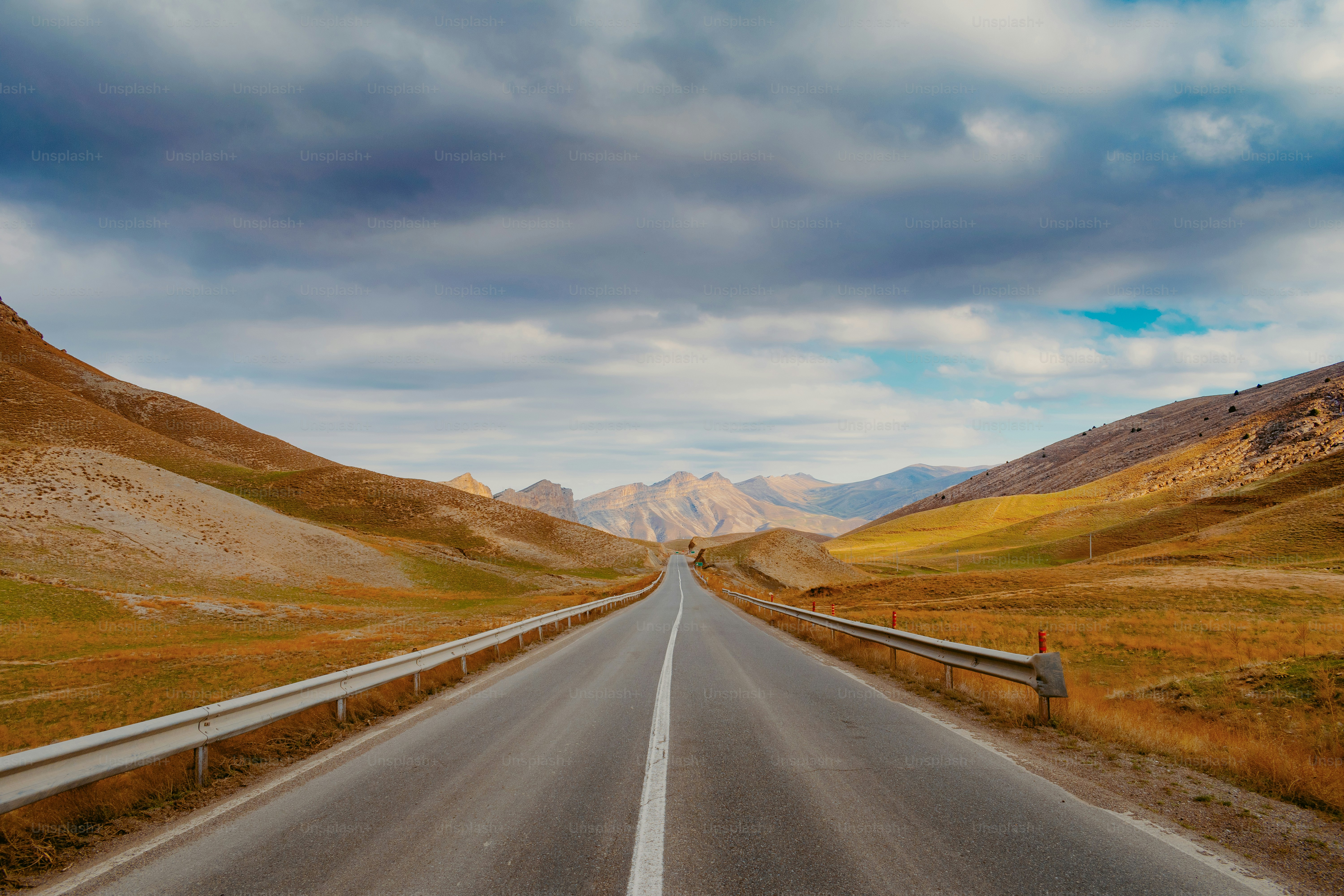 an empty road in the middle of a mountain range