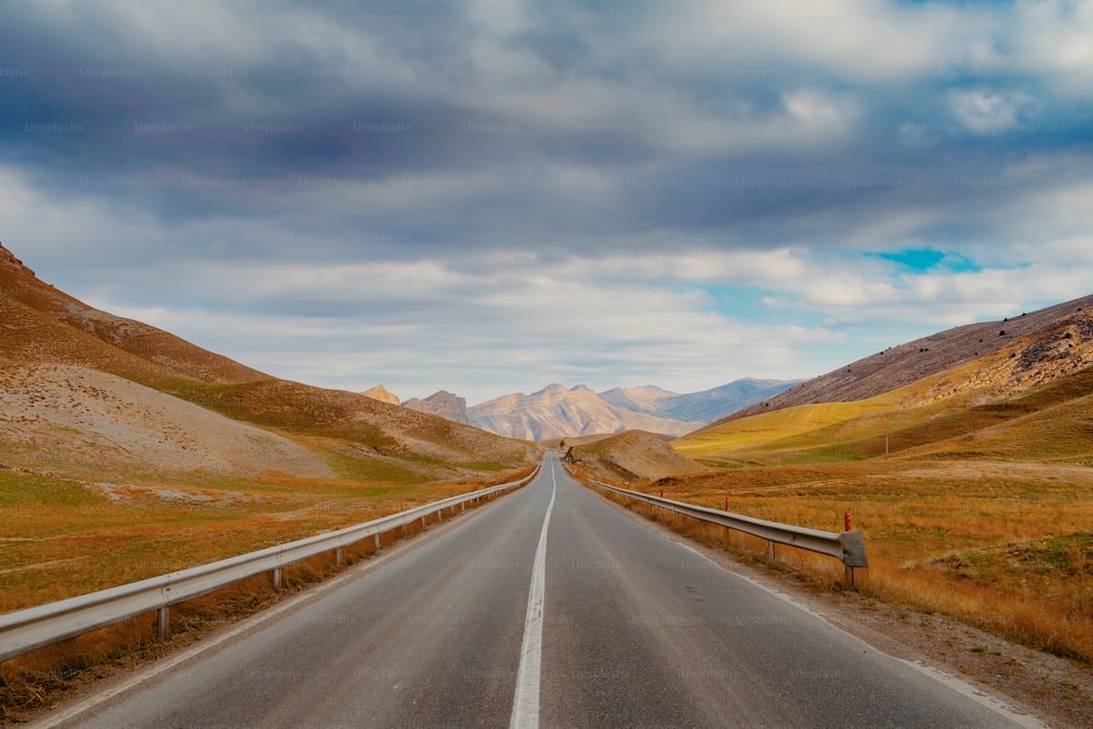 an empty road in the middle of a mountain range