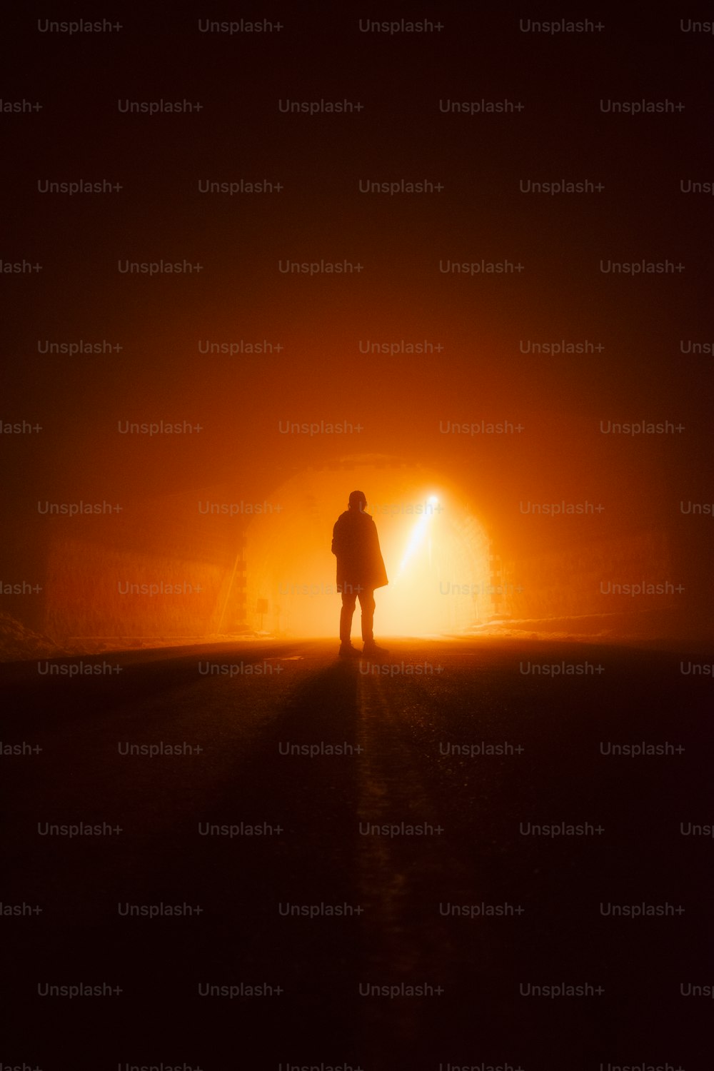 una persona in piedi in mezzo a una strada buia