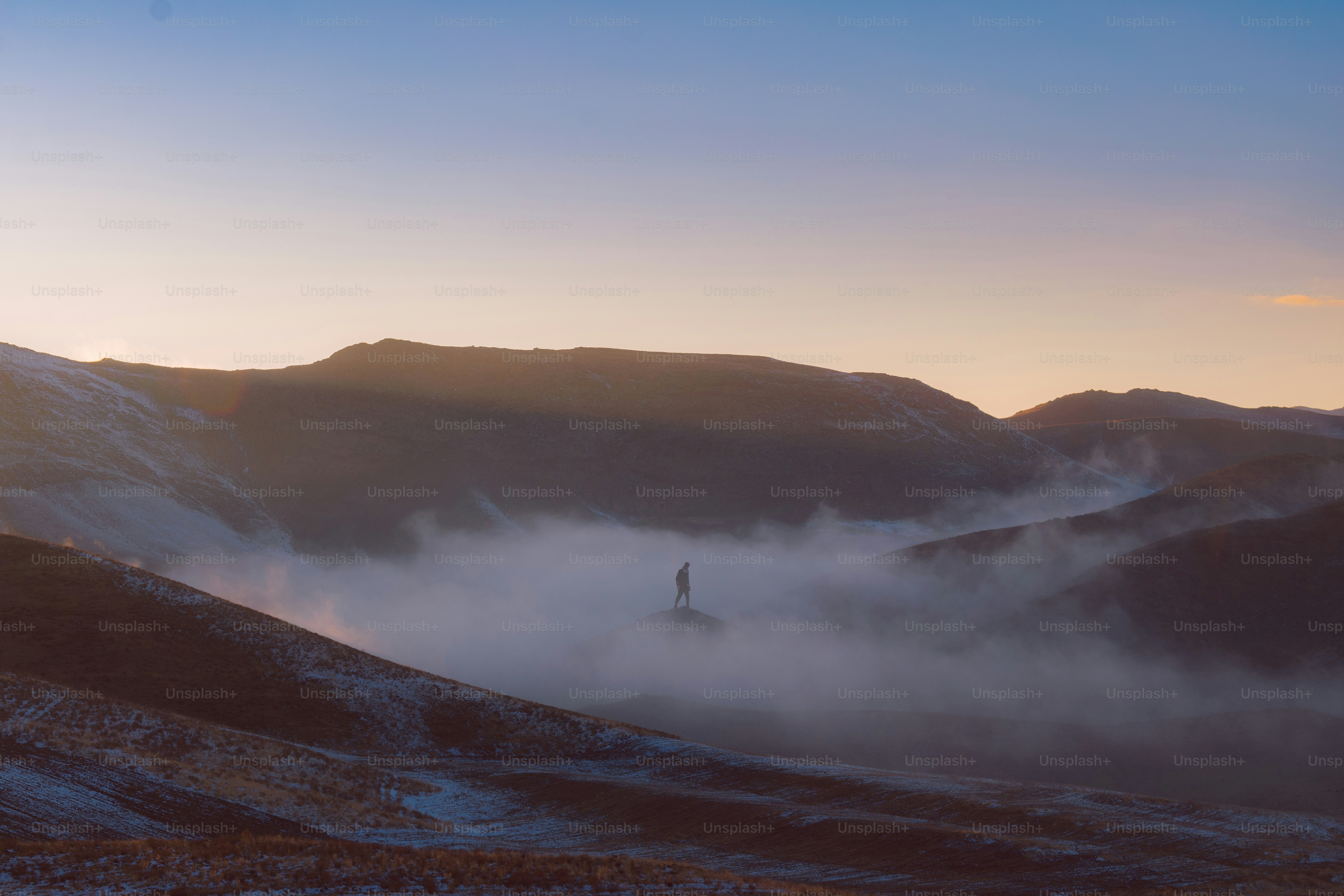 une personne debout au sommet d’une montagne enneigée
