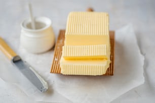 um pedaço de manteiga sentado em cima de uma tábua de corte ao lado de uma faca
