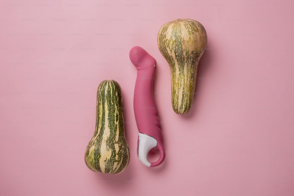 a couple of gourds sitting on top of a pink surface