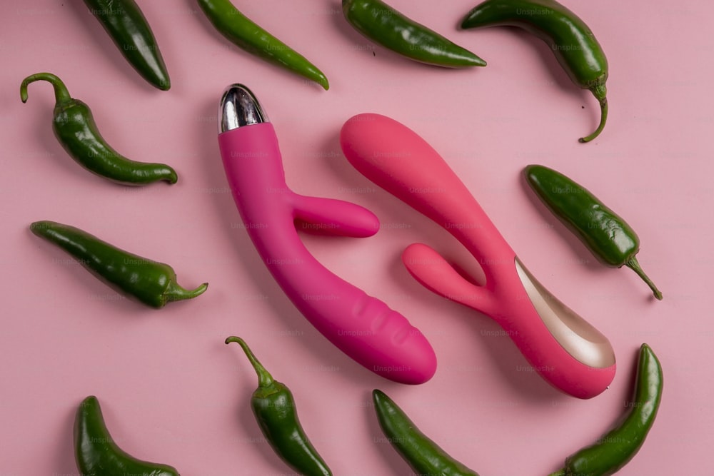 a group of green and pink peppers on a pink surface