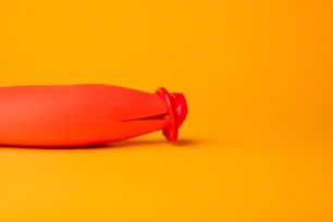 an orange object with a red cap on a yellow background