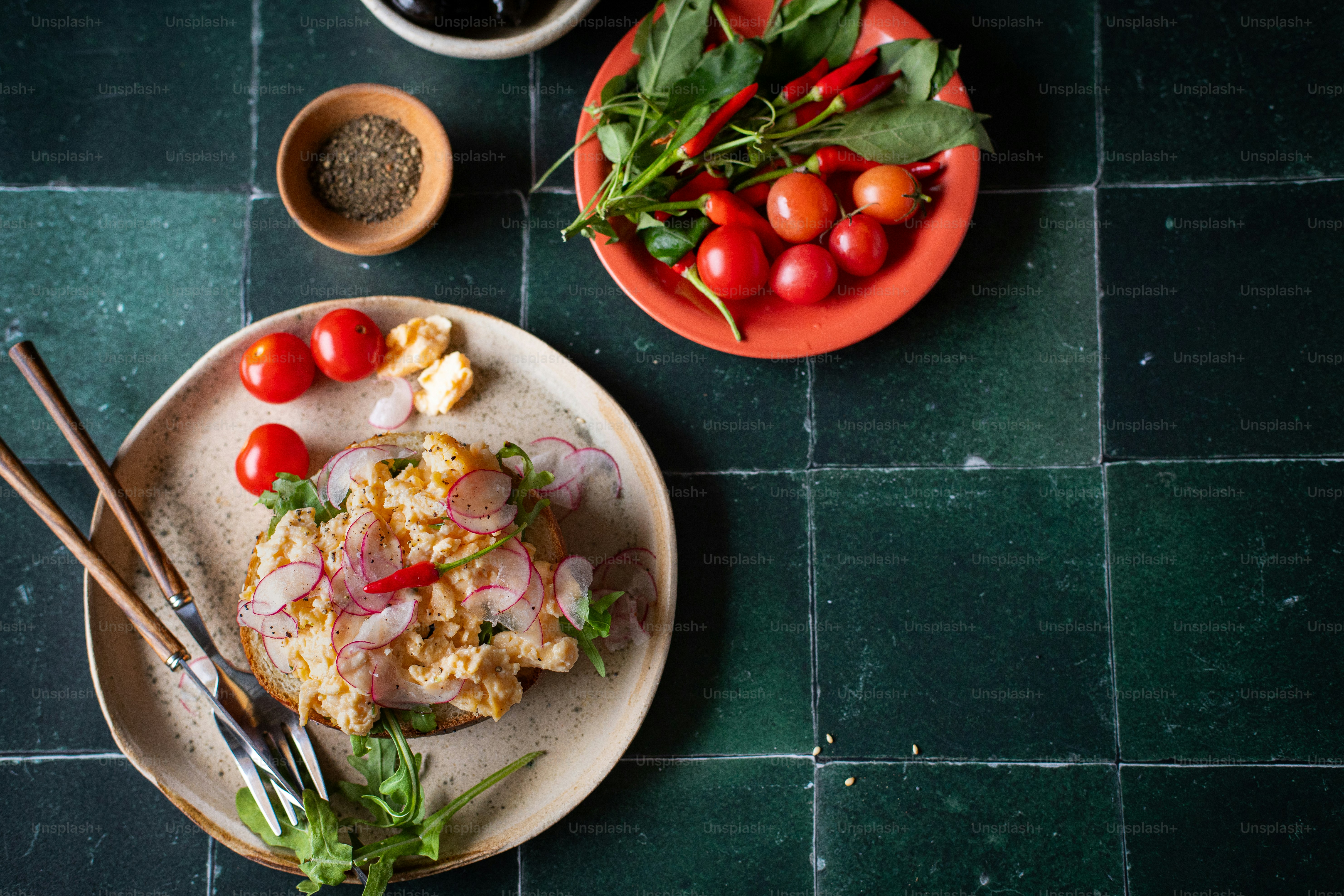 a plate of food on a table next to a bowl of tomatoes
