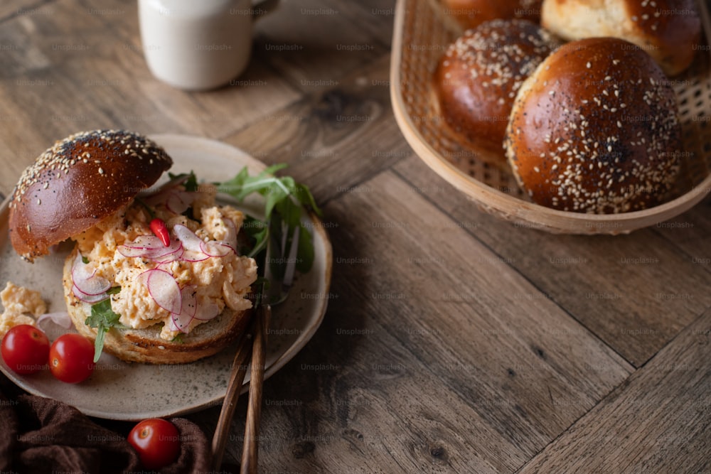 a sandwich on a plate next to a basket of rolls