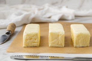 four pieces of cheese on a cutting board with a knife