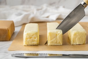 a knife cutting a block of cheese on a cutting board