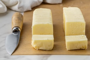 um par de pedaços de queijo sentado em cima de uma tábua de corte